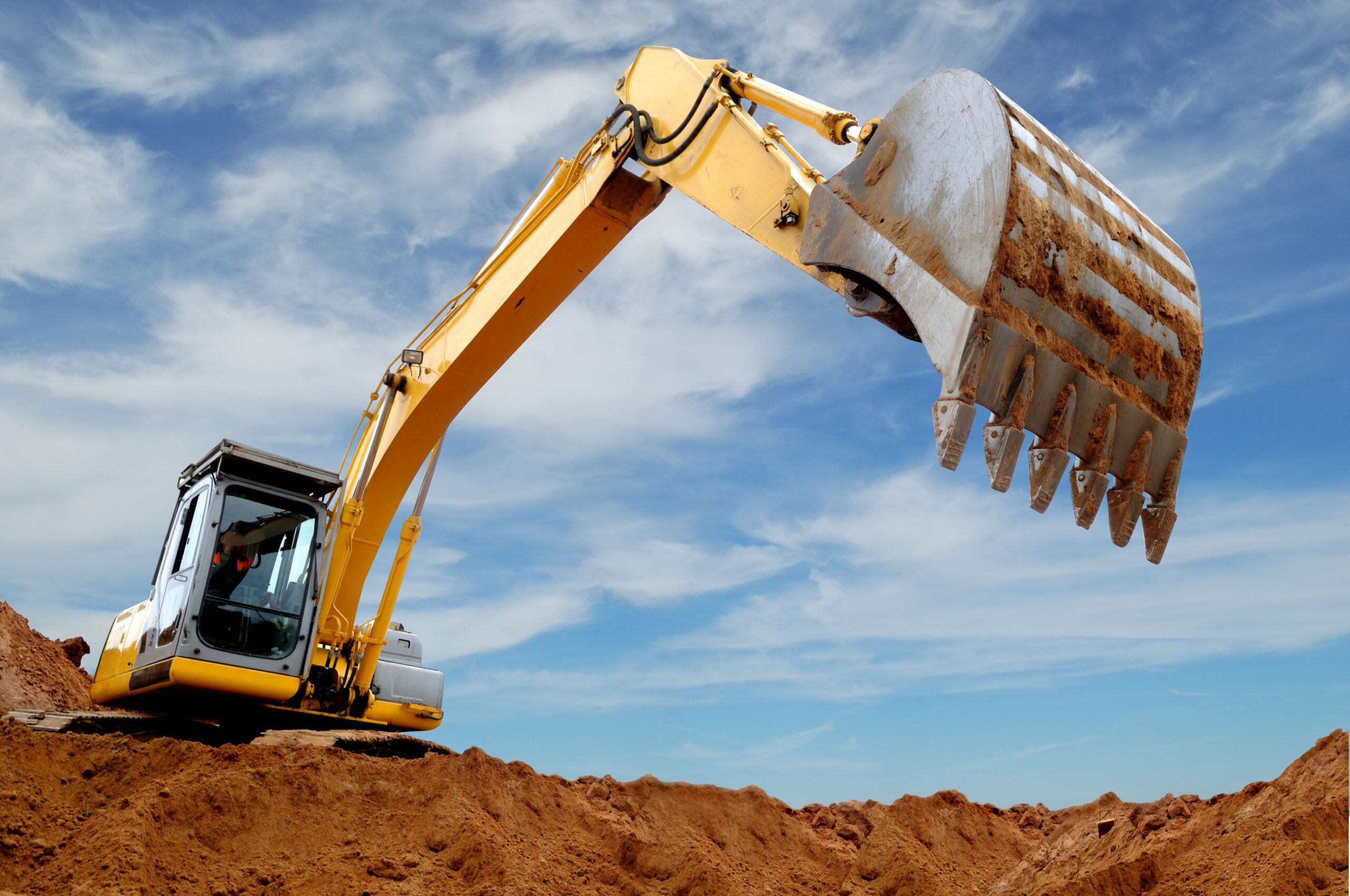 6154646 - excavator standing in sandpit with raised bucket over cloudscape sky